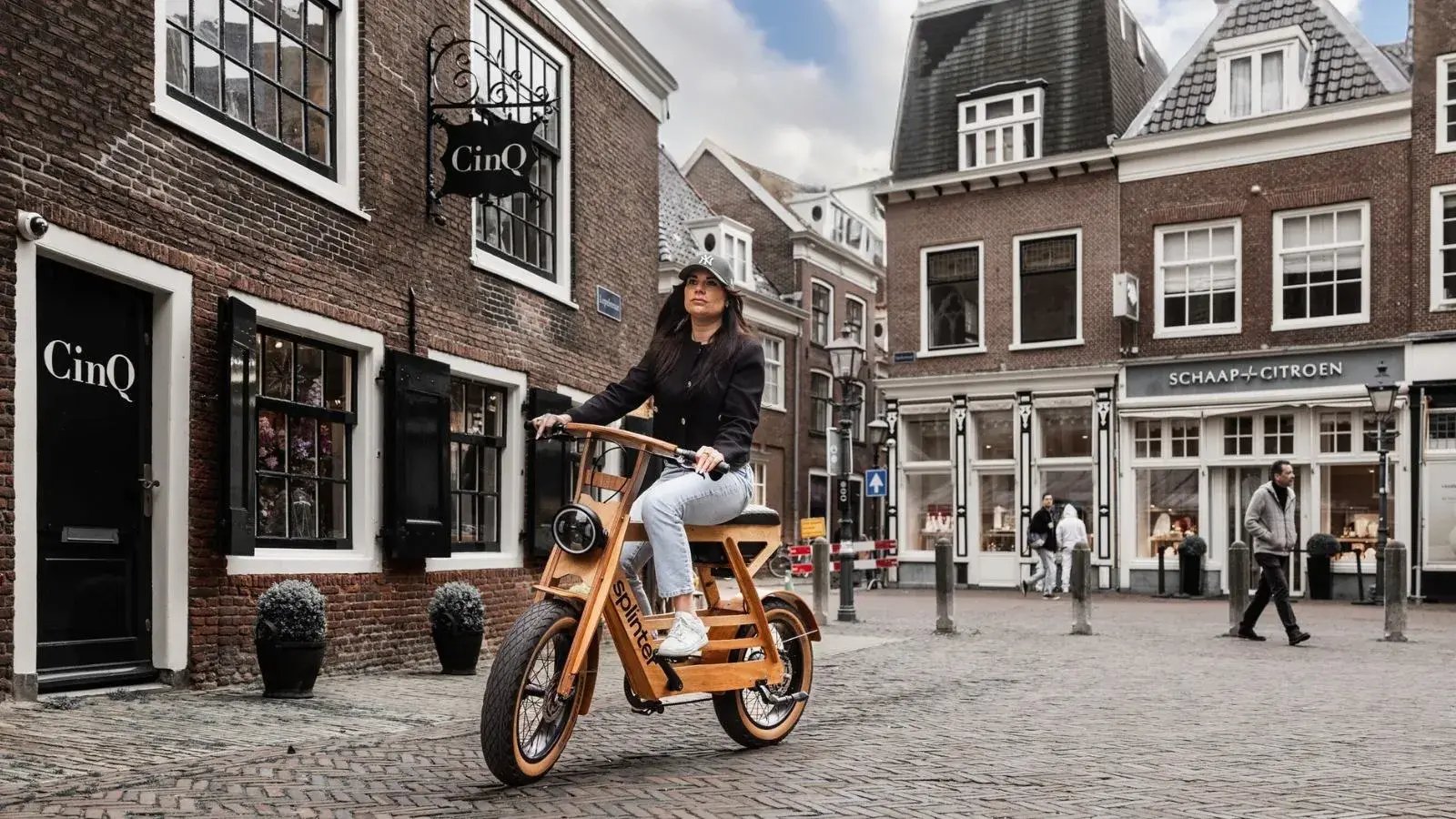Vrouw rijdt op een handgemaakte elektrische fiets van Splinter Bikes door een stadsomgeving — houten fatbike, design fiets kopen